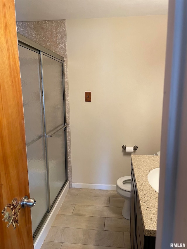 bathroom featuring vanity, toilet, and a shower with shower door