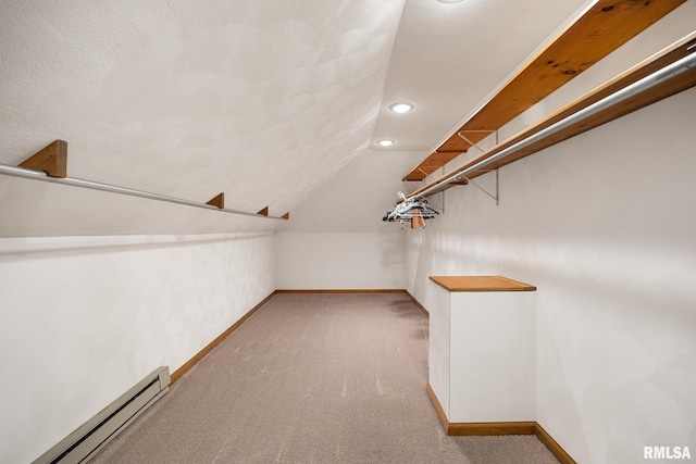 spacious closet with lofted ceiling, a baseboard heating unit, and light colored carpet