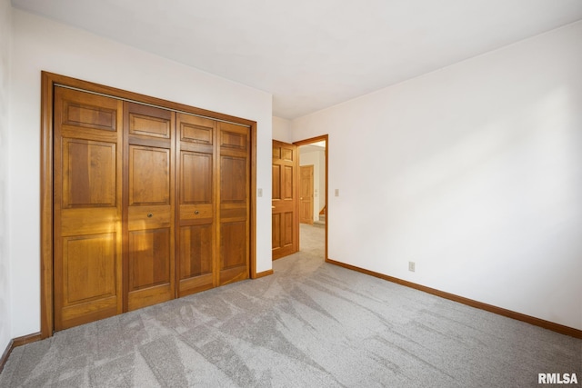 unfurnished bedroom with light colored carpet and a closet