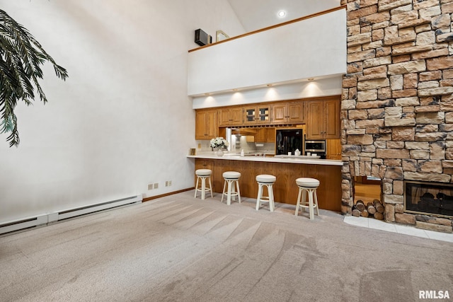 kitchen featuring kitchen peninsula, high vaulted ceiling, a breakfast bar, light colored carpet, and black refrigerator