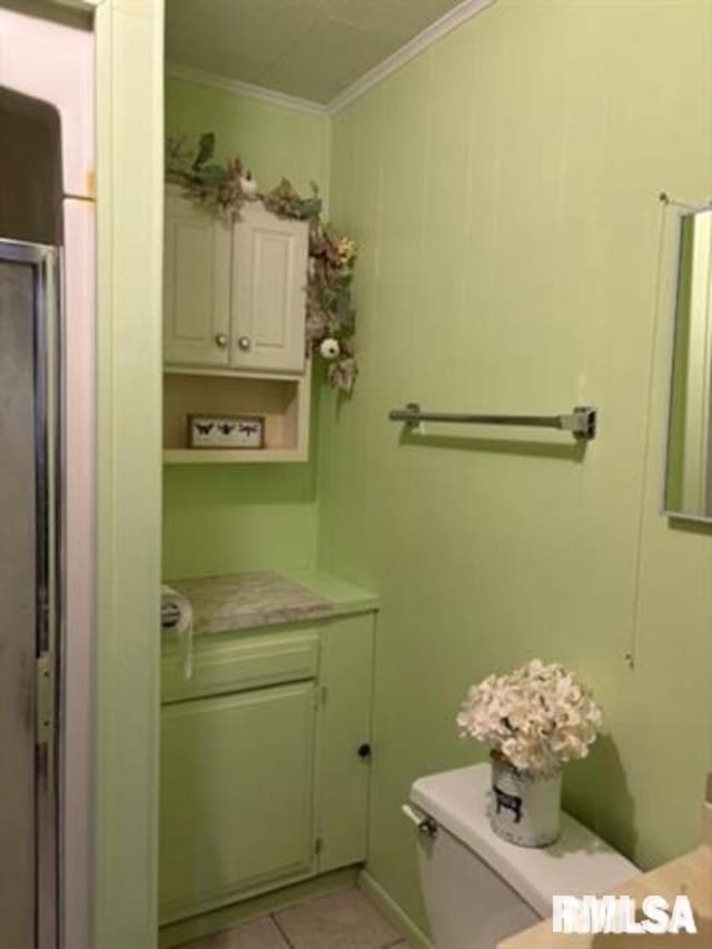 bathroom with toilet, crown molding, and tile patterned floors