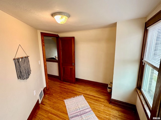 empty room with a textured ceiling and light wood-type flooring