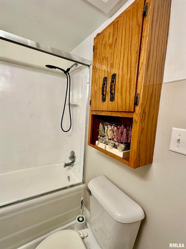 bathroom with toilet, tile walls, and bathing tub / shower combination