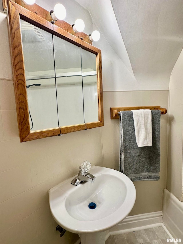 bathroom featuring tile walls, sink, tile patterned floors, and vaulted ceiling