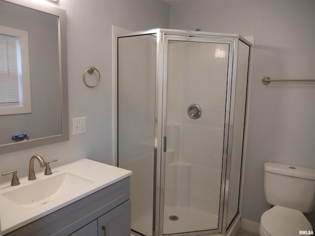 bathroom with toilet, a stall shower, and vanity