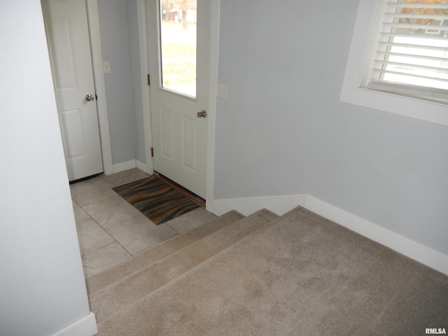 entryway featuring light tile patterned floors, light colored carpet, and baseboards