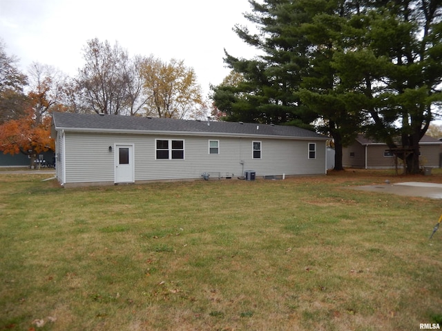 rear view of property featuring a lawn and central AC unit