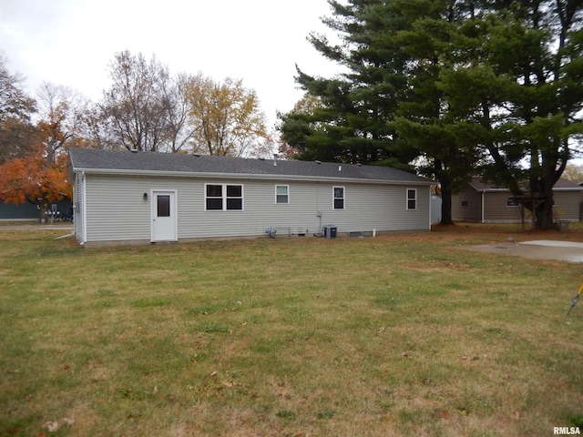 rear view of property featuring central AC unit and a yard