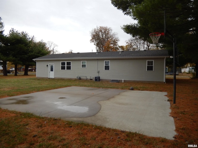 rear view of property featuring basketball court, a patio area, a lawn, and central air condition unit