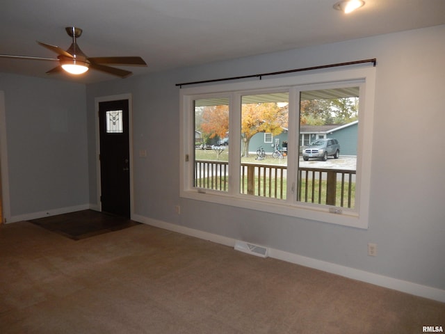 carpeted empty room with visible vents, ceiling fan, and baseboards