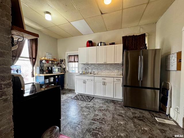 kitchen with backsplash, sink, white cabinets, appliances with stainless steel finishes, and a paneled ceiling