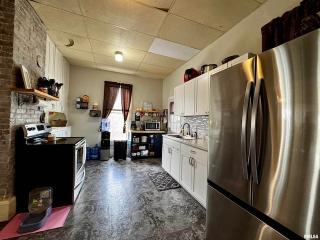 kitchen with decorative backsplash, appliances with stainless steel finishes, white cabinetry, a paneled ceiling, and sink