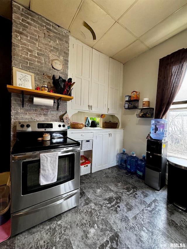 kitchen with a drop ceiling, white cabinetry, and stainless steel electric range oven