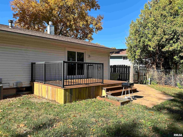 rear view of house with a wooden deck, a yard, and a patio