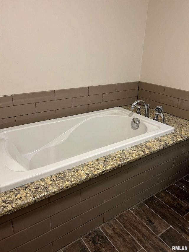 bathroom featuring wood-type flooring and tiled bath