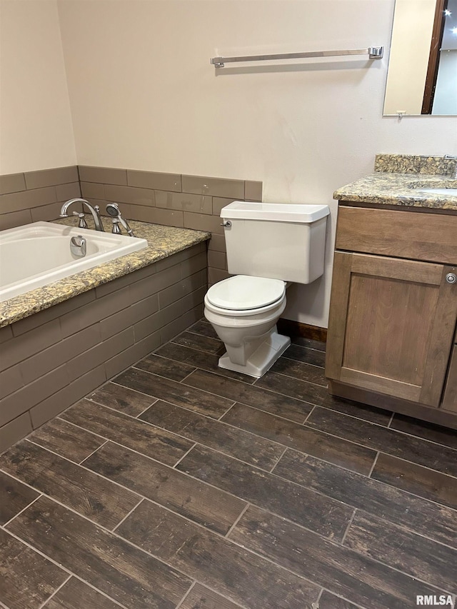 bathroom with hardwood / wood-style flooring, toilet, a relaxing tiled tub, and vanity