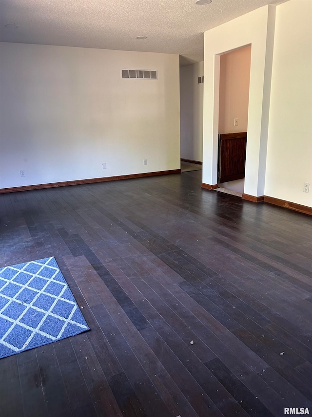 spare room with dark wood-type flooring and a textured ceiling