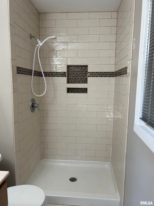 bathroom with vanity, toilet, and a tile shower