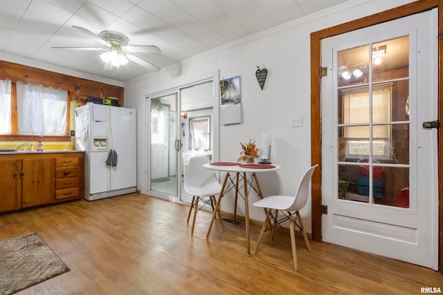 kitchen featuring light hardwood / wood-style floors, ornamental molding, white fridge with ice dispenser, and a healthy amount of sunlight