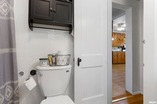 bathroom with wood-type flooring, toilet, and tile walls