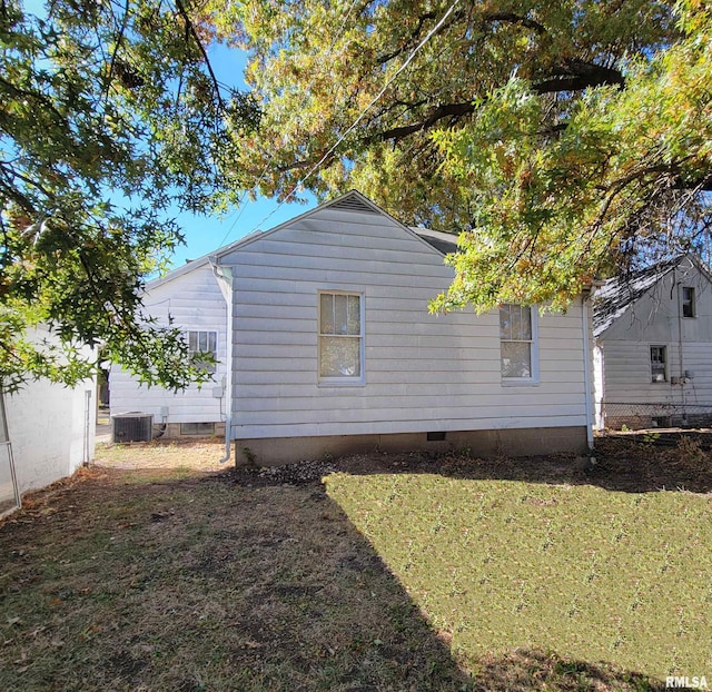 view of side of home with crawl space, central air condition unit, fence, and a lawn