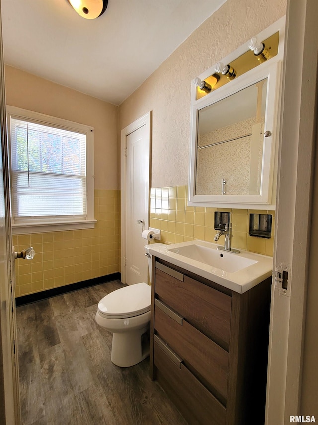 bathroom with hardwood / wood-style floors, vanity, toilet, and tile walls