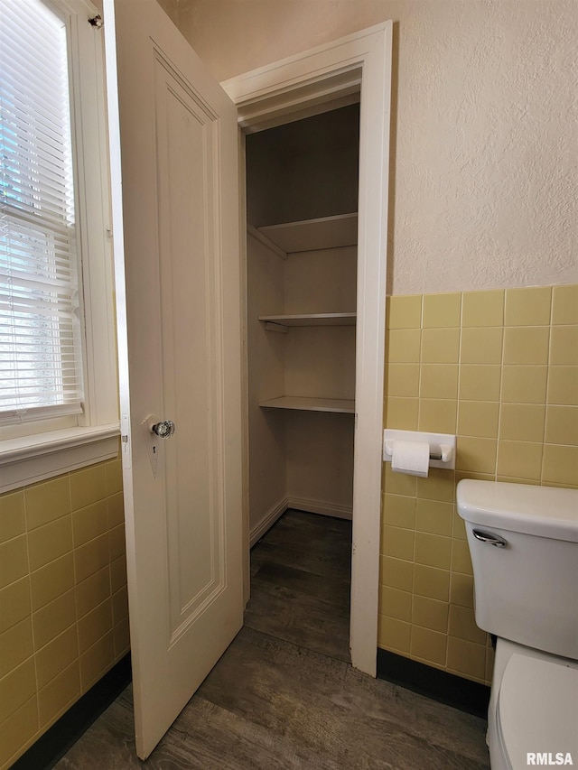 bathroom with tile walls, hardwood / wood-style floors, and toilet