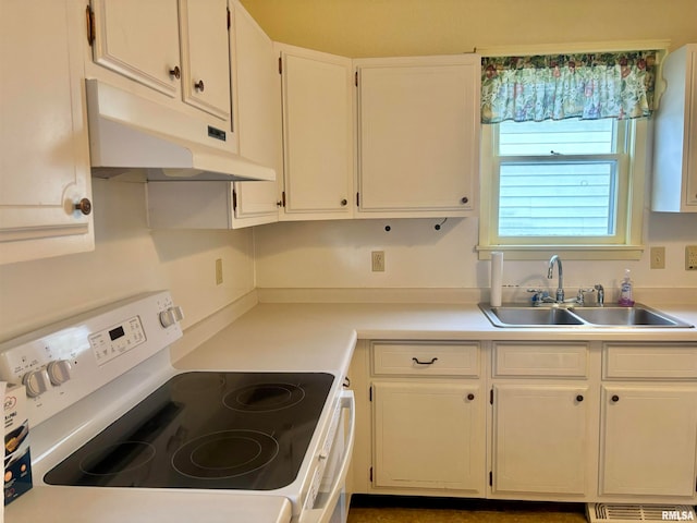 kitchen with white electric range oven, white cabinets, and sink