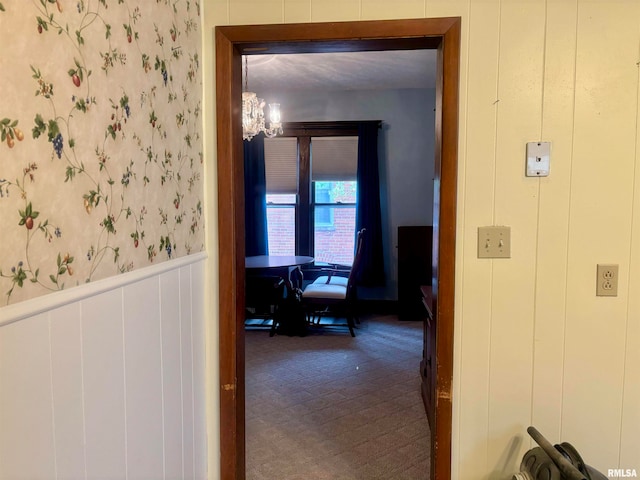 corridor with wood walls and an inviting chandelier