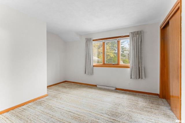 empty room with carpet, a textured ceiling, and a baseboard radiator