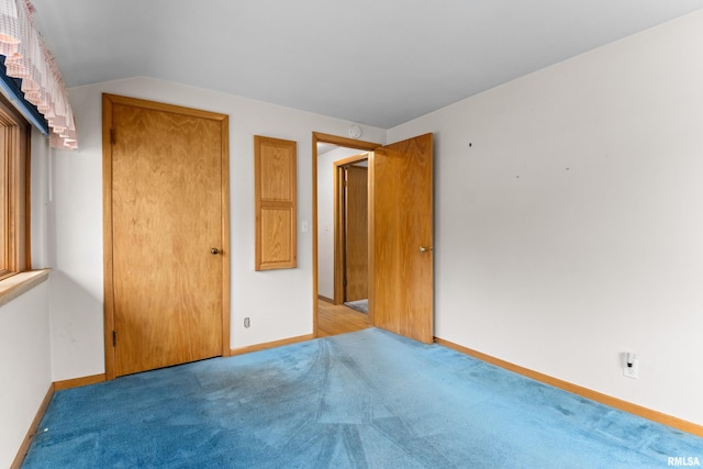 unfurnished bedroom with light colored carpet and lofted ceiling