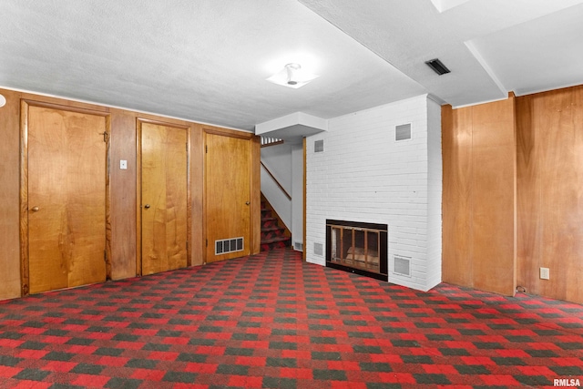 basement featuring a large fireplace, dark carpet, and a textured ceiling