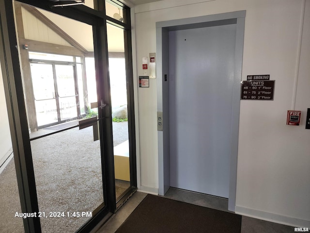 doorway featuring elevator and carpet