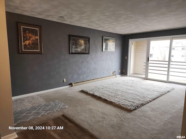 carpeted spare room with a baseboard radiator and a textured ceiling