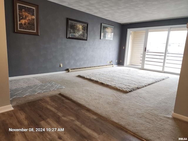 spare room featuring a textured ceiling, a baseboard radiator, and dark hardwood / wood-style floors