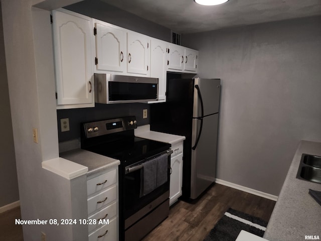 kitchen featuring dark hardwood / wood-style flooring, white cabinetry, sink, and appliances with stainless steel finishes