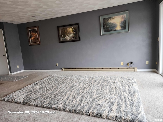 carpeted spare room with a textured ceiling and a baseboard heating unit