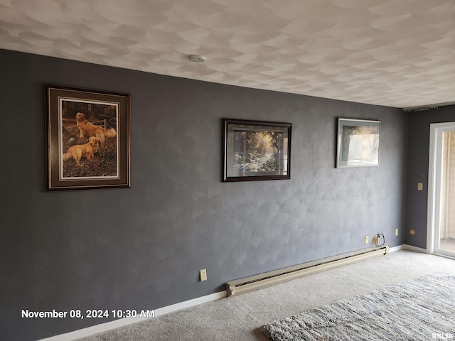 empty room featuring a baseboard heating unit and carpet