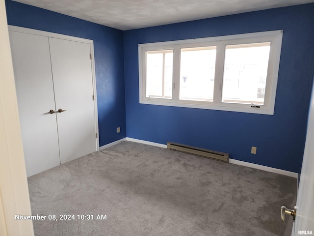 unfurnished bedroom featuring a closet, light colored carpet, and a baseboard radiator