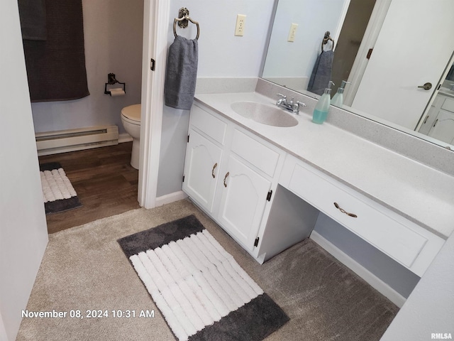 bathroom with hardwood / wood-style flooring, baseboard heating, vanity, and toilet