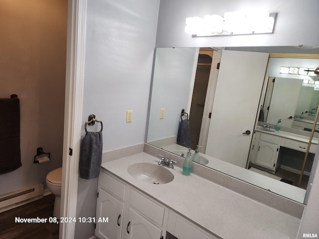 bathroom with toilet, vanity, and a baseboard heating unit