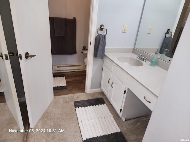 bathroom featuring vanity, hardwood / wood-style flooring, a baseboard radiator, and toilet