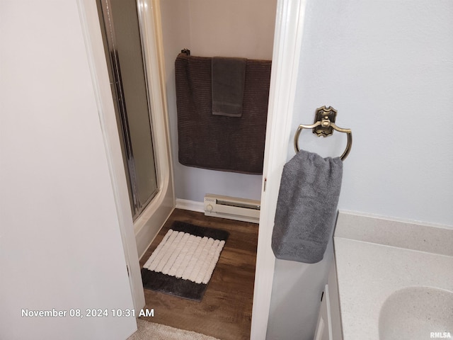 bathroom with hardwood / wood-style flooring, vanity, an enclosed shower, and a baseboard heating unit