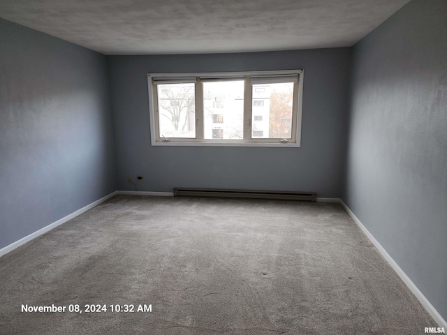 carpeted empty room featuring a baseboard heating unit and a textured ceiling