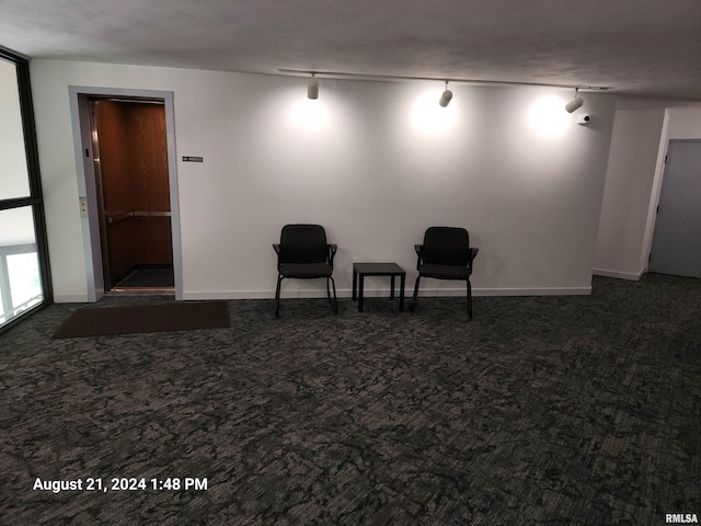 living area featuring track lighting and dark colored carpet