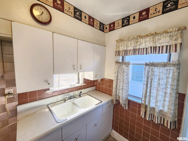 kitchen featuring sink, white cabinets, and tile walls