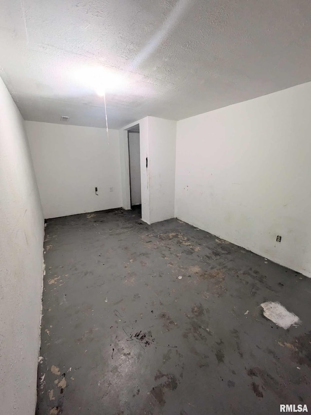 empty room with a textured ceiling and concrete floors