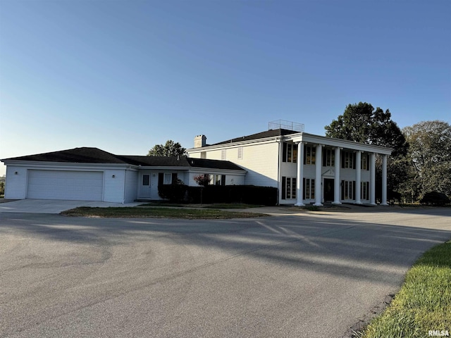 2001 Wigwam Hollow Rd, Macomb, IL 61455 - neoclassical home featuring an attached garage, concrete driveway, and a chimney