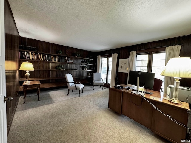 office area featuring light colored carpet, a textured ceiling, and wooden walls