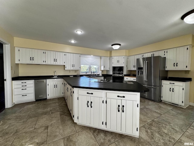 2001 Wigwam Hollow Rd, Macomb, IL 61455 - kitchen featuring appliances with stainless steel finishes, dark countertops, white cabinets, and a peninsula